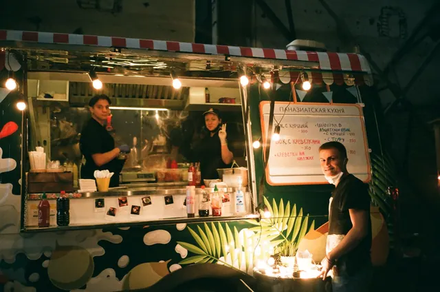 Group of coworkers standing near street food truck while working and looking at camera at nights. Food truck commissary requirements by city: what gets inspected