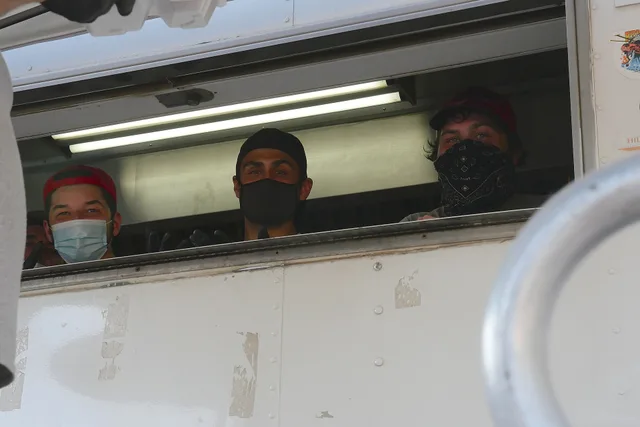 Temperature checks and face coverings are part of daily life in fire camp. Food service workers wear face coverings. Photo depicts three individuals peeking from a window in a food catering truck wearing face coverings. 8.22.2020_RedSalmonComplex_InCamp_SRF_Romney_P1150483 Forest Service photo by Ke. Food truck hiring: build the team around the stations