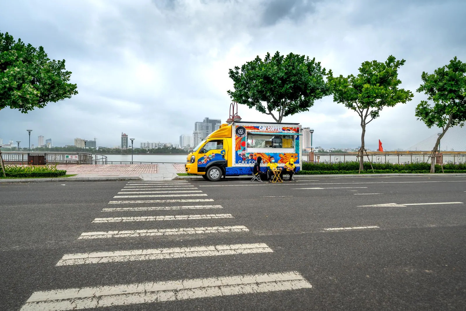 A vibrant food truck parked on an empty city street with a scenic riverside view. How to get a food truck permit in BC: steps and costs