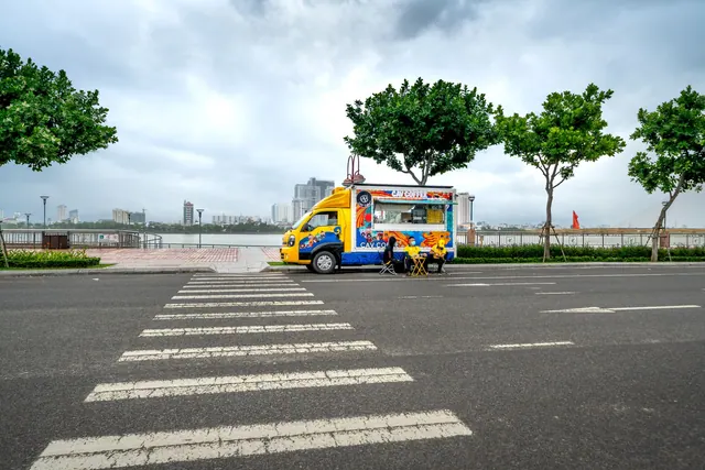 A vibrant food truck parked on an empty city street with a scenic riverside view. How to get a food truck permit in BC: steps and costs