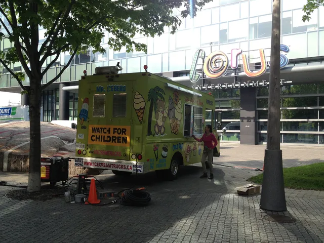 A Mr. Iceberg ice cream truck, City of Toronto permit #942, Ontario license plate AB 31576, outside Corus Quay, Toronto, Ontario. Vehicle is marked with "www.IceCreamTrucks.ca". Appears partially connected to a Honda EU7000is power generator. Transfer a food truck permit: approval or new application